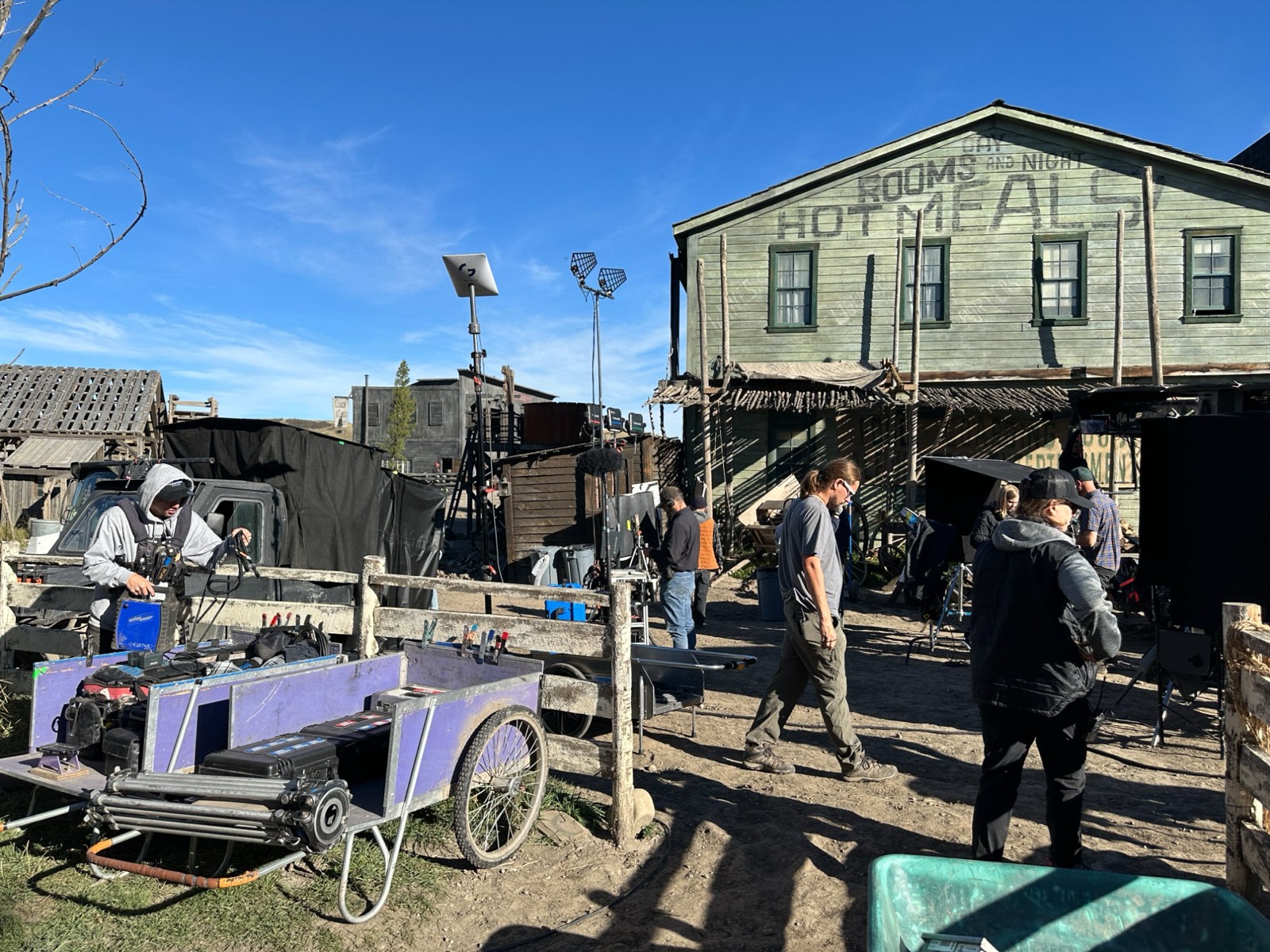 Film crew working in western town set with Genstate equipment visible